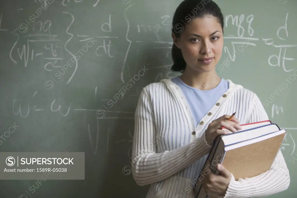 Young woman holding books standing in a classroom