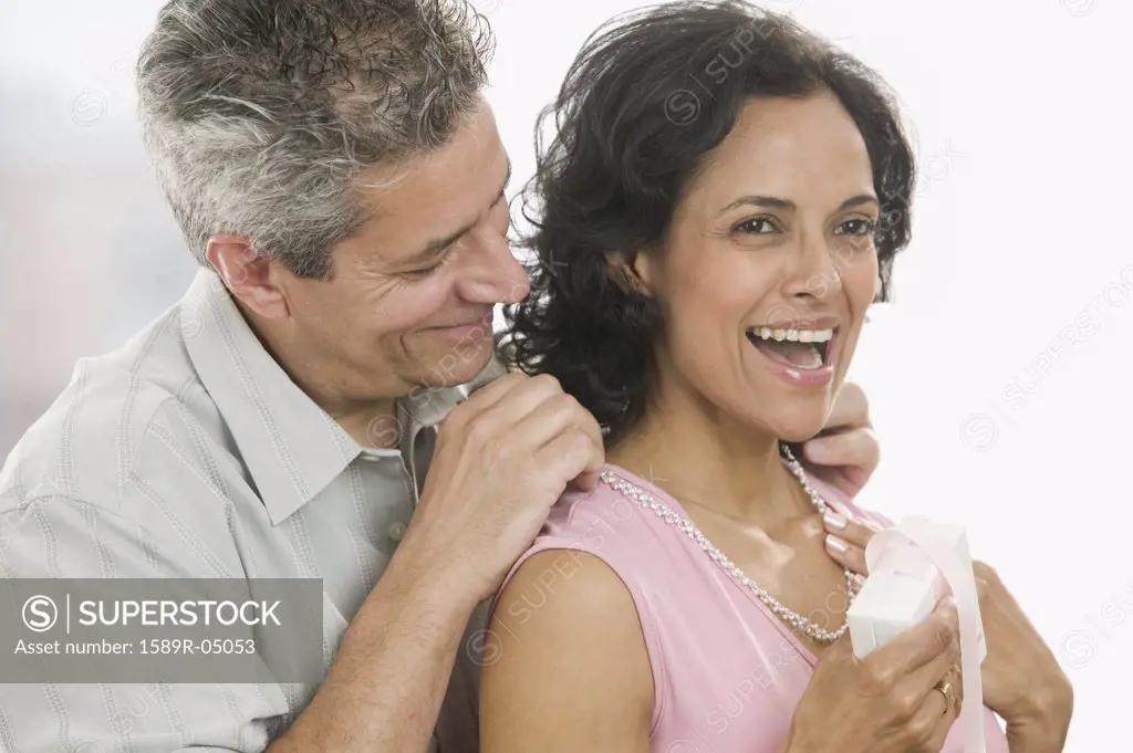 Man helping a woman put on a necklace