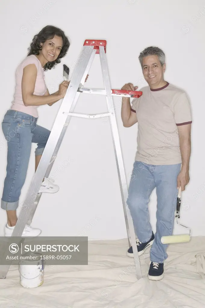 Couple standing on a ladder painting a wall
