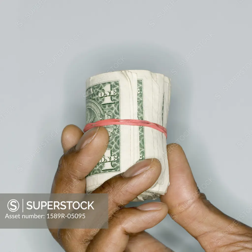 Human hand holding a roll of bank notes