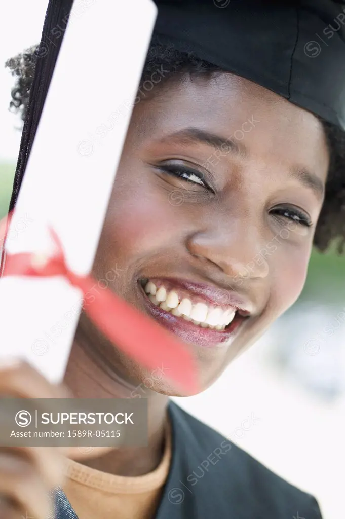 Young female graduate holding a diploma looking at camera smiling