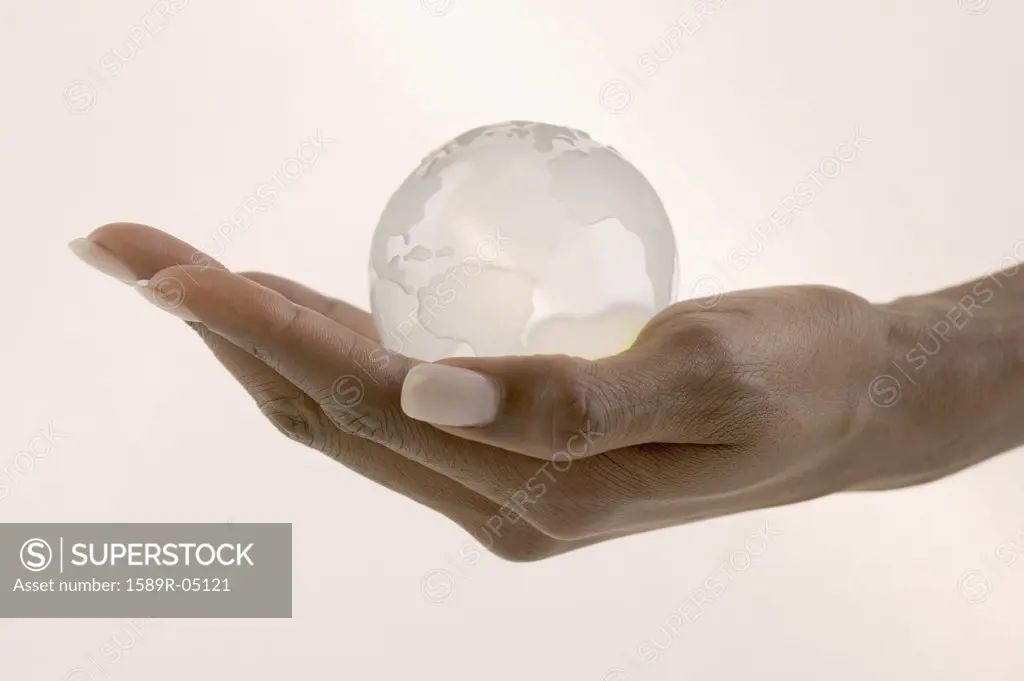 Woman's hand holding a glass globe in the palm of her