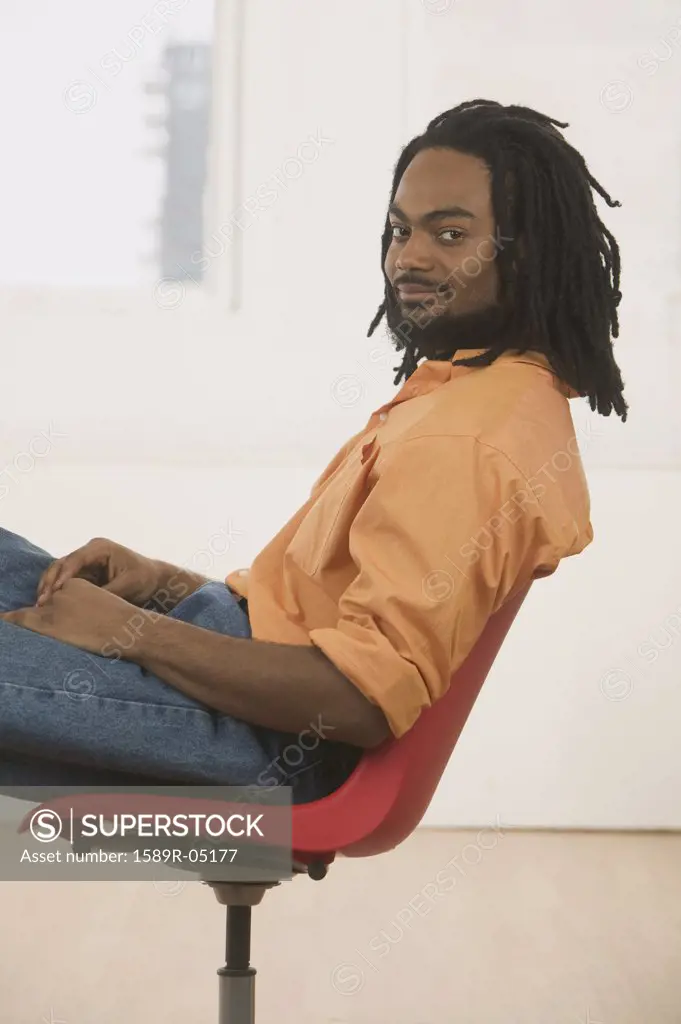 Young man sitting on a chair looking at camera