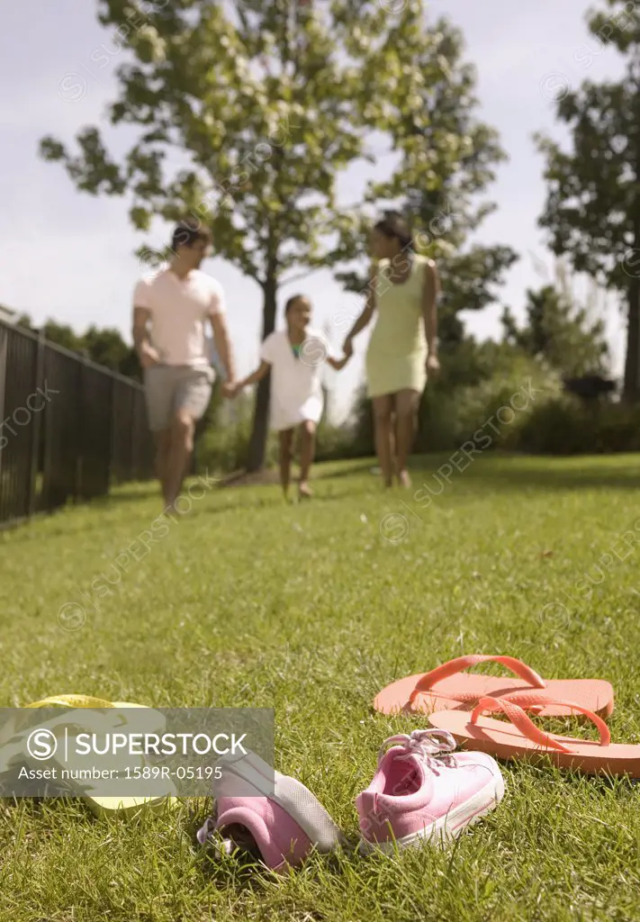 Low angle view of a young couple and their child running on a lawn
