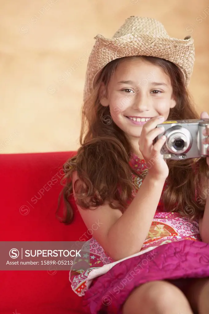 Young girl sitting on a couch holding a camera