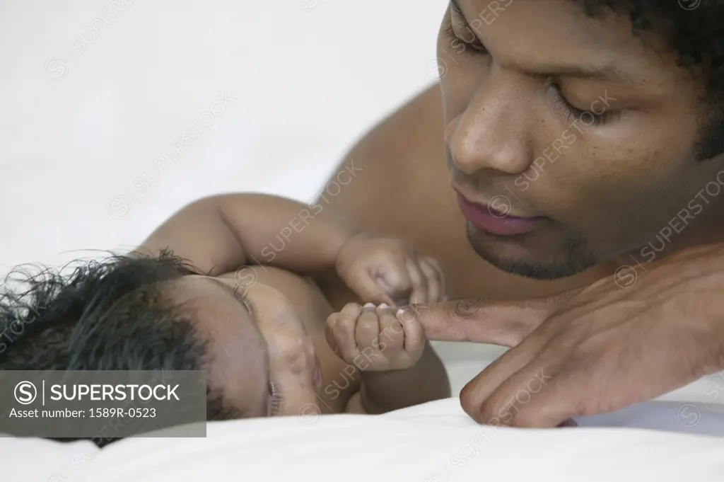 Young man lying on a bed holding a baby