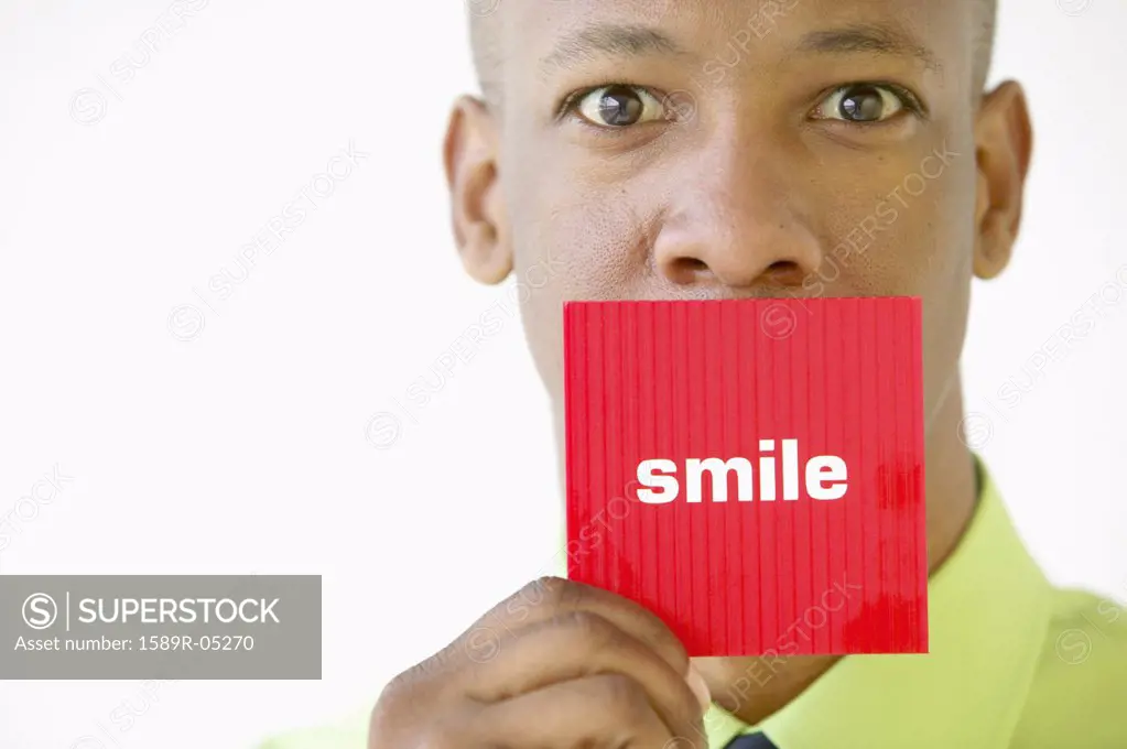 Portrait of a businessman holding up a card with the word smile written