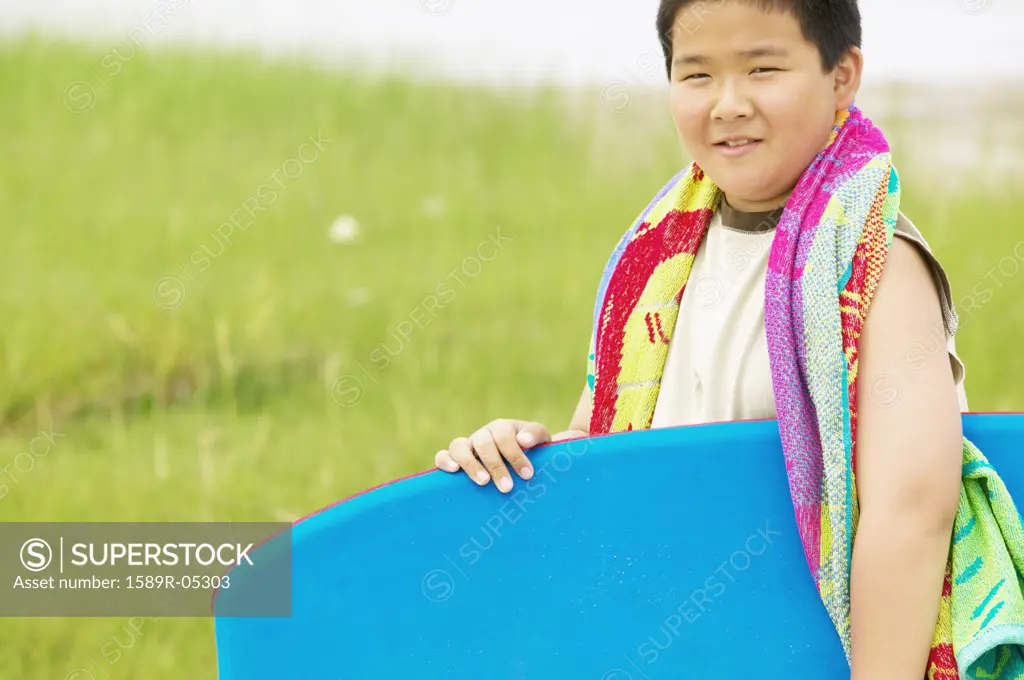 Young boy holding a boogie board smiling