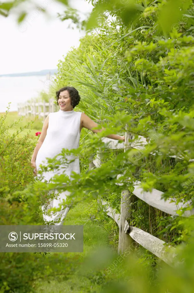 Mid adult woman standing leaning against a fence