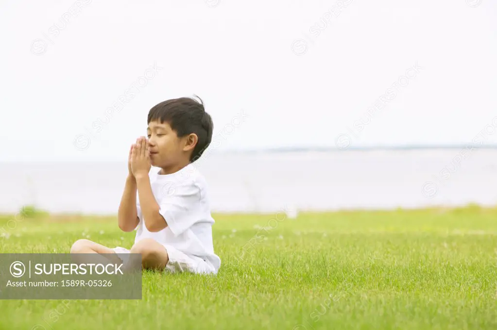 Young boy meditating on the lawn