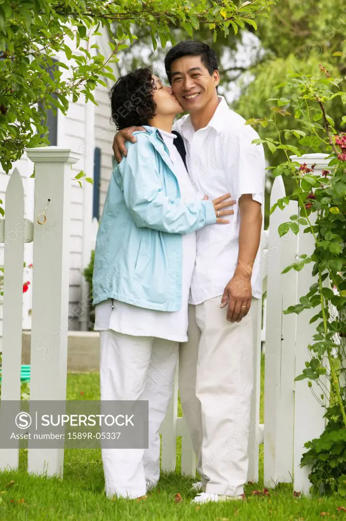 Woman kissing a man standing together on a lawn