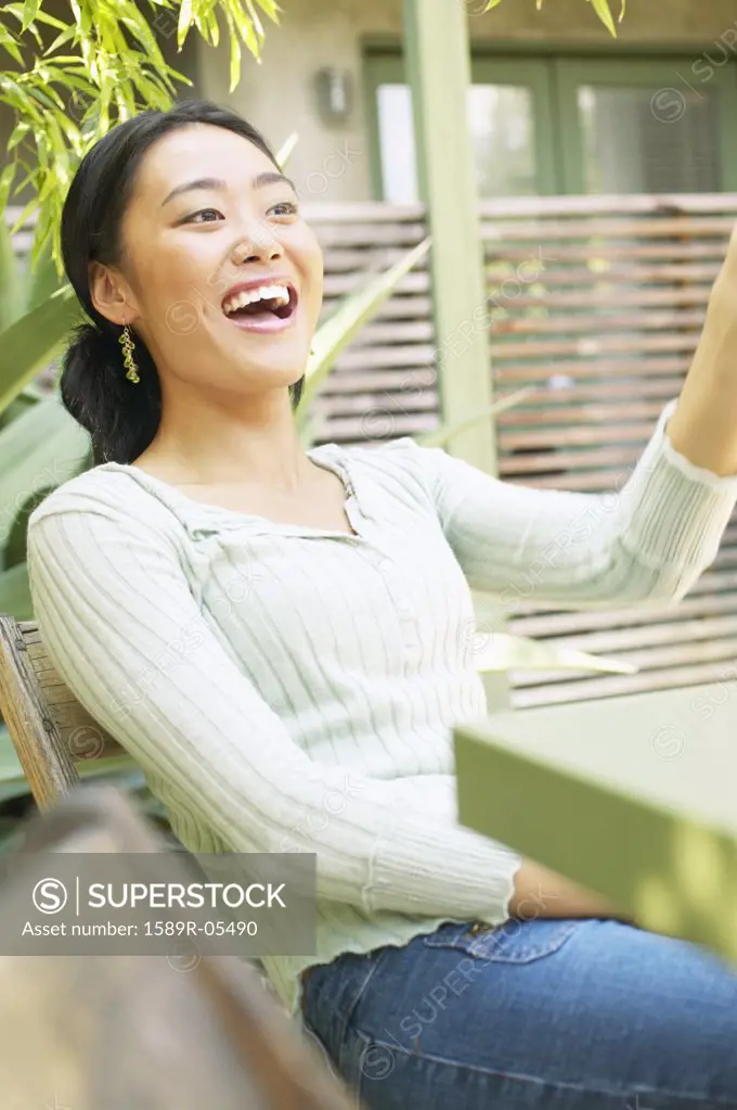 Young woman sitting on a chair outdoors smiling