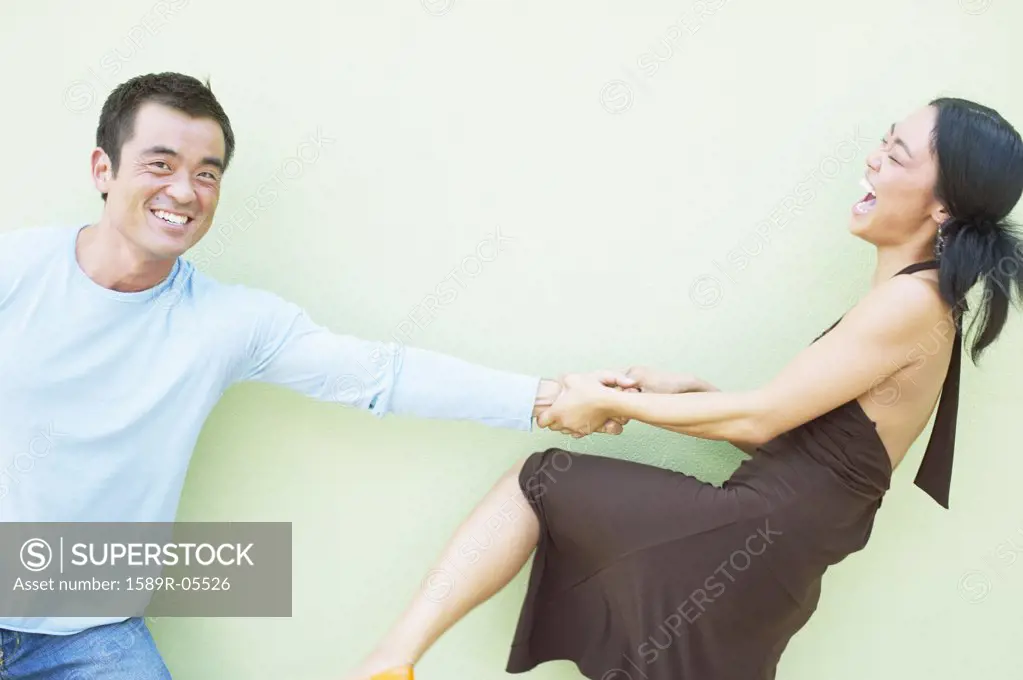Young woman pulling a mid adult man by his arm