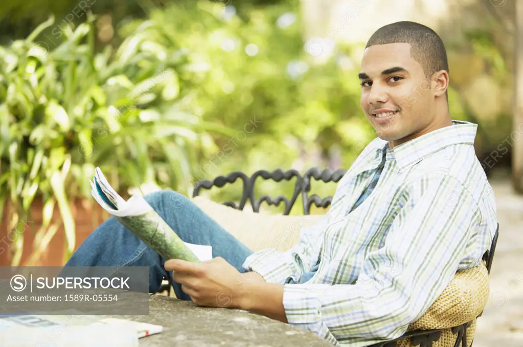 Portrait of a young man sitting at a table holding a magazine