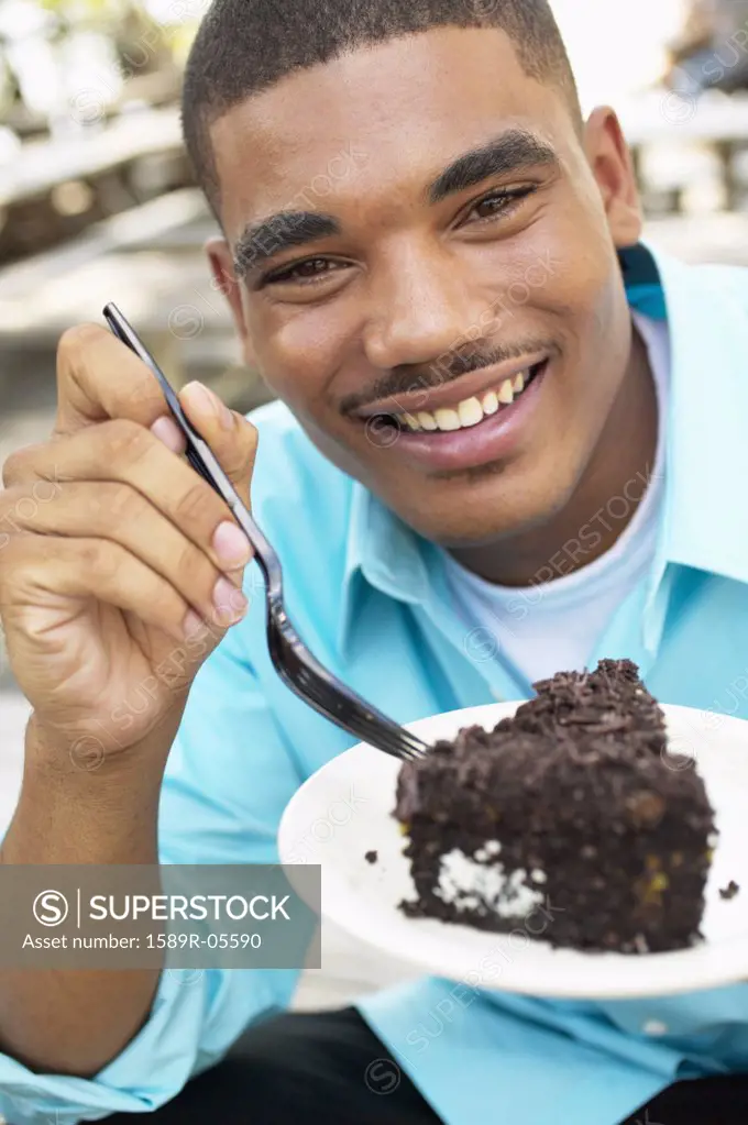 Portrait of a young man eating a piece of cake