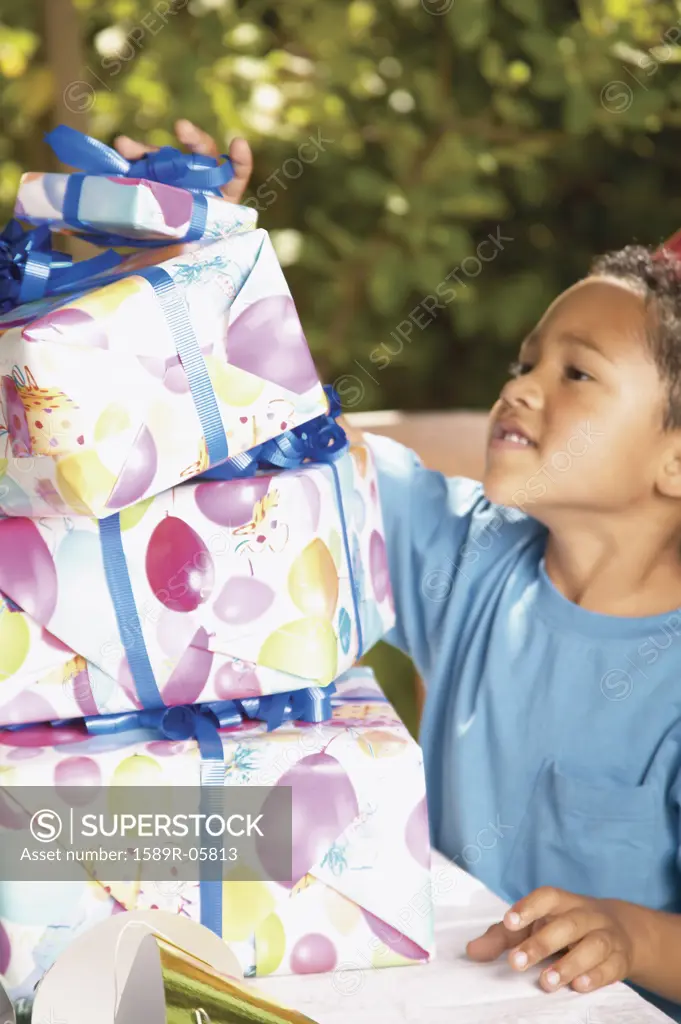 Side profile of a young boy standing next to a stack of presents