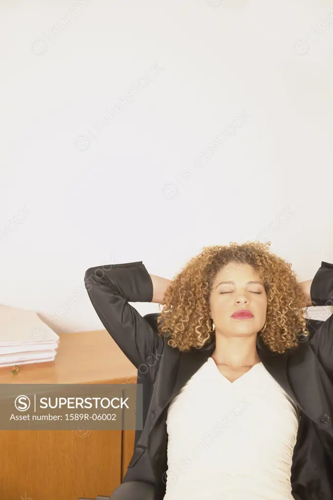 Young businesswoman relaxing on a chair with her hands behind her head