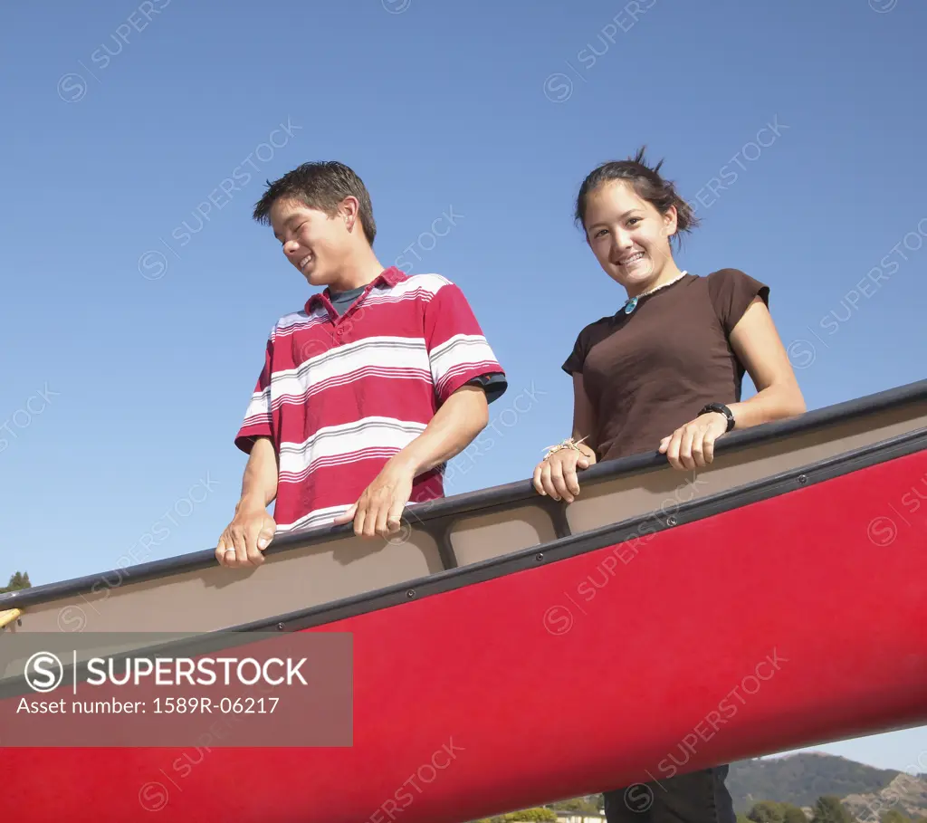 Young couple holding a row boat and smiling