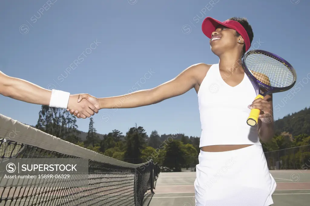 Young woman shaking hands with a man over a tennis net
