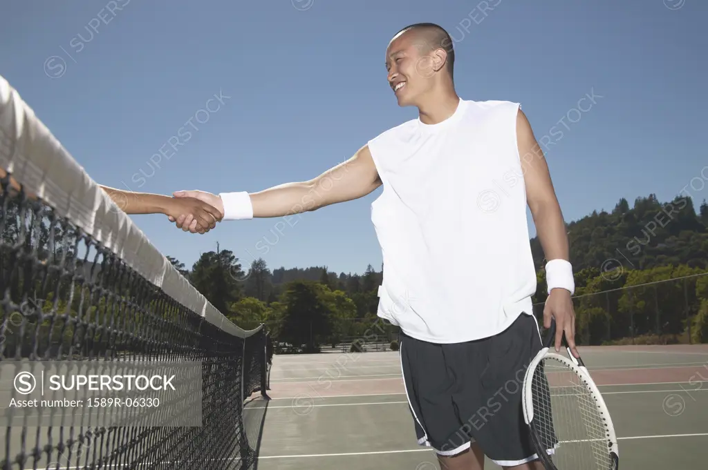 Young man shaking hand with a woman over a tennis net