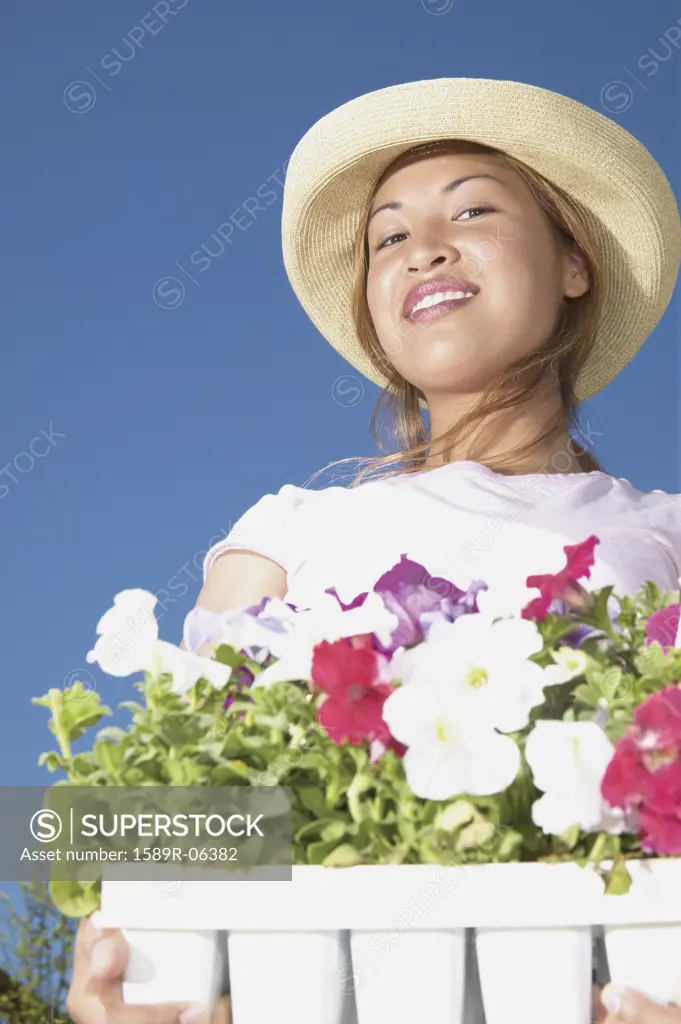 Young woman standing in a garden holding potted plants smiling