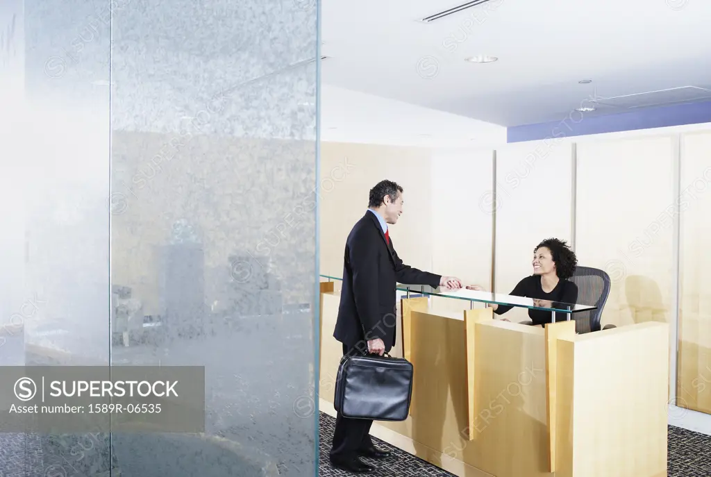 Side profile of a businessman talking to a receptionist in an office