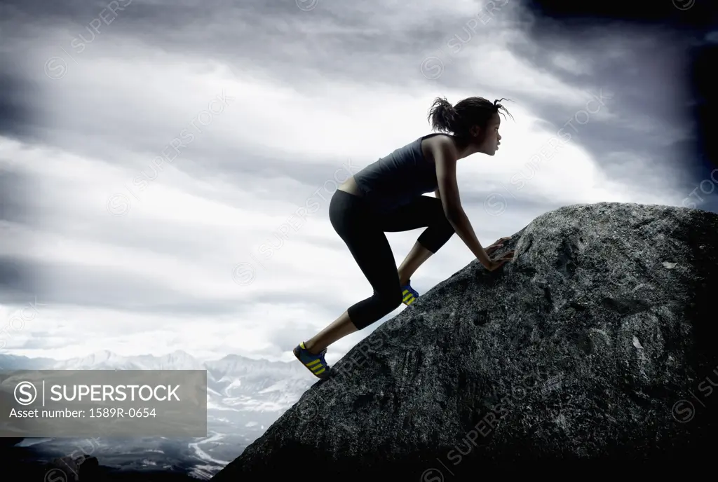 Young woman climbing up a rock face