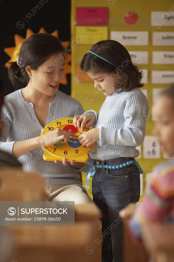 Female teacher and her student holding a clock