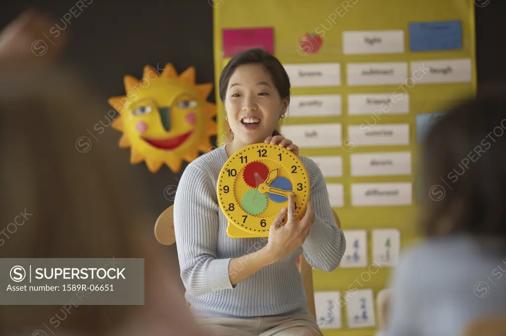 Female teacher showing a clock to the students in a classroom