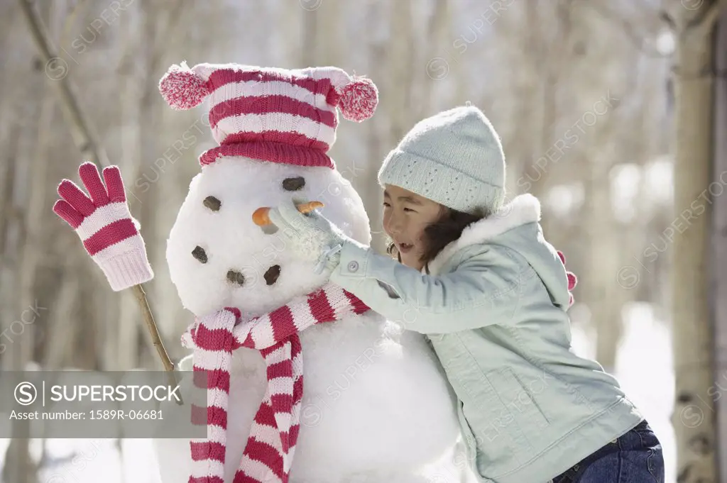 Close-up of a girl fixing a carrot on a snowman's face