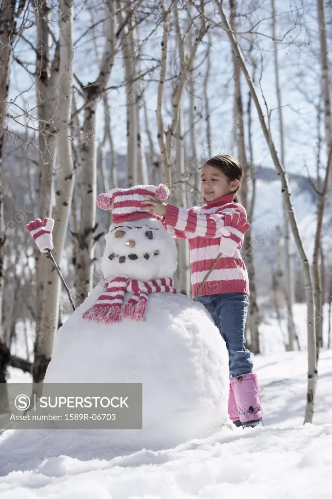 Girl putting a bobble hat on a snowman