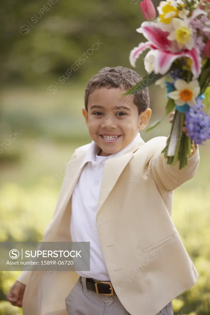 Portrait of a boy holding a bouquet of flowers in a field