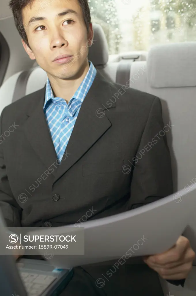 Mid adult businessman sitting in a car with a laptop in front of him