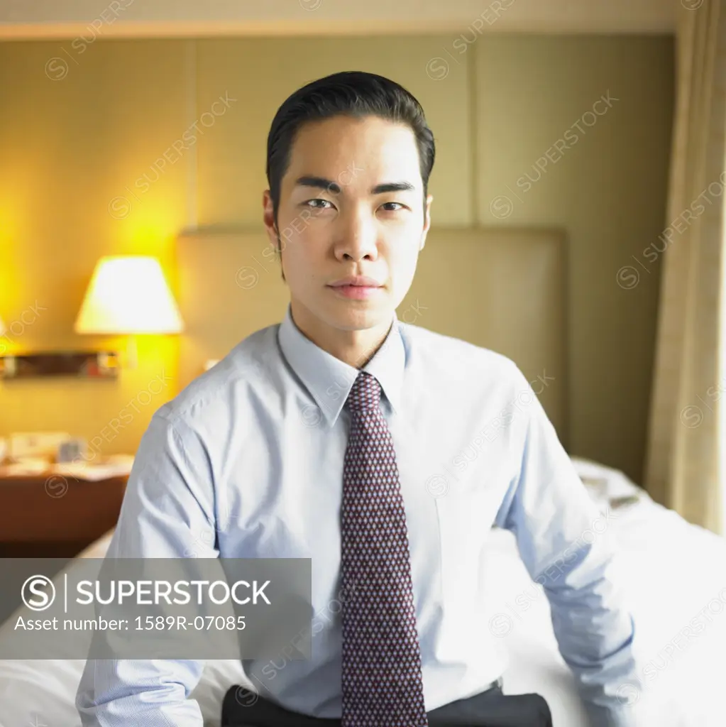 Portrait of a young businessman sitting on a bed