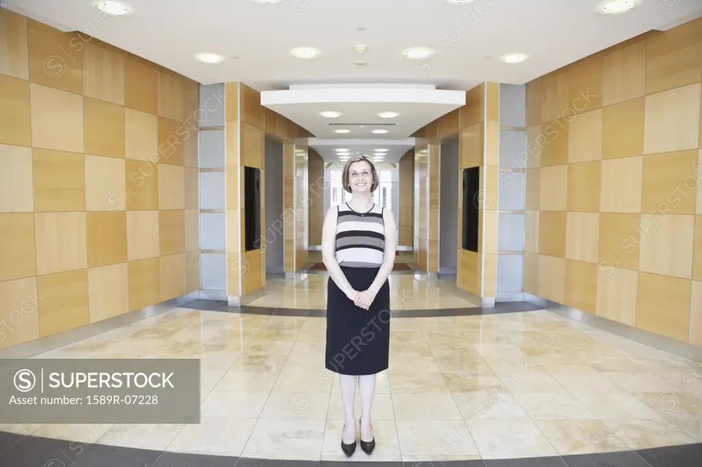 Portrait of a businesswoman standing in a corridor with her hands clasped