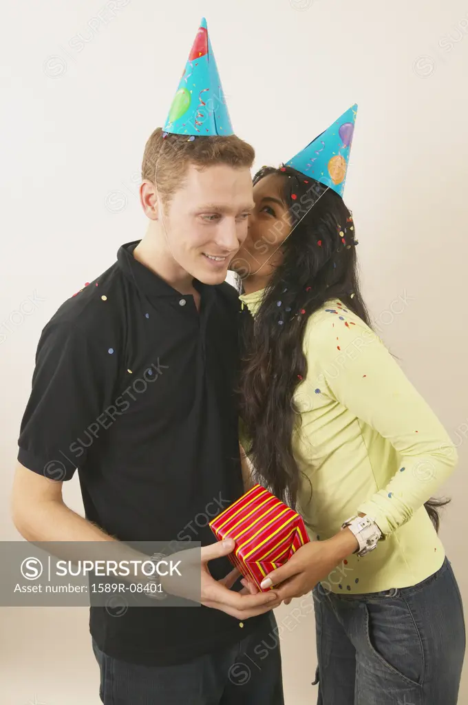 Young woman kissing a young man at a birthday party
