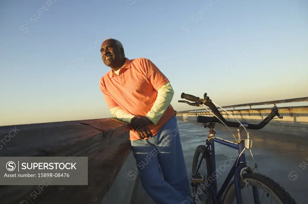 Mature man leaning against railing on a bridge