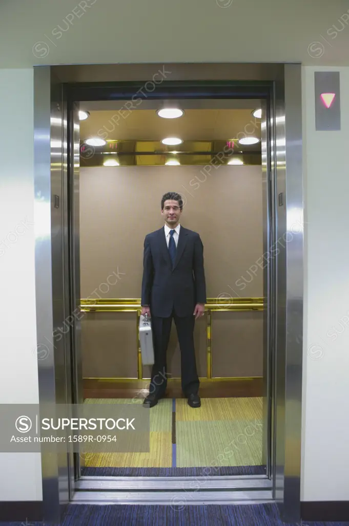 Young businessman standing in an elevator with a briefcase