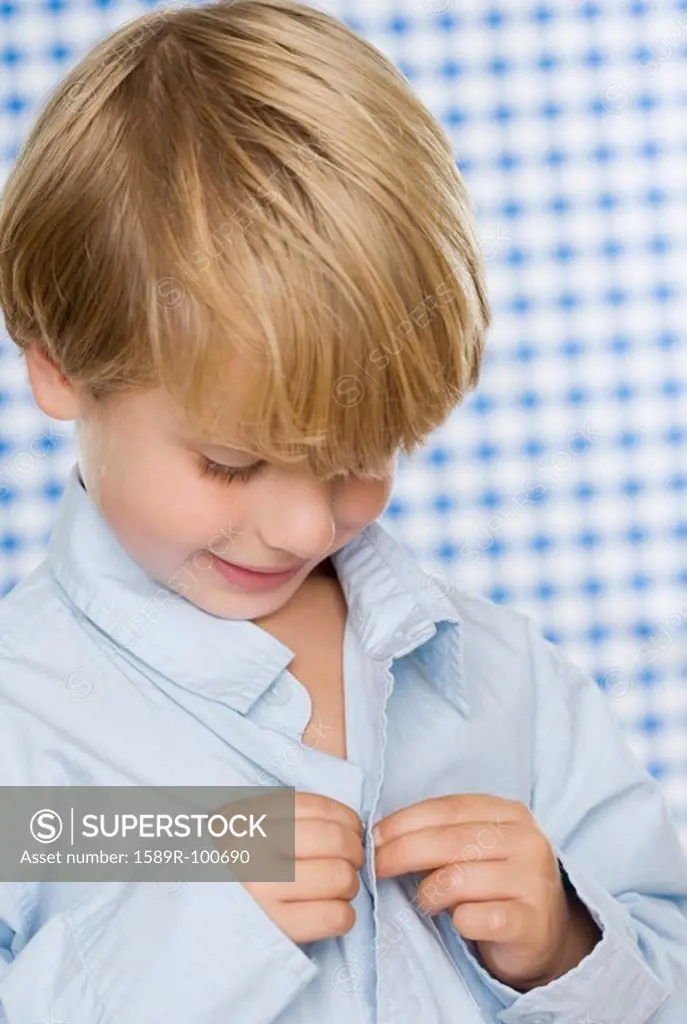 Young boy buttoning shirt