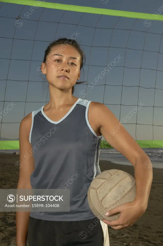 Portrait of a young woman holding a volley in front of a net