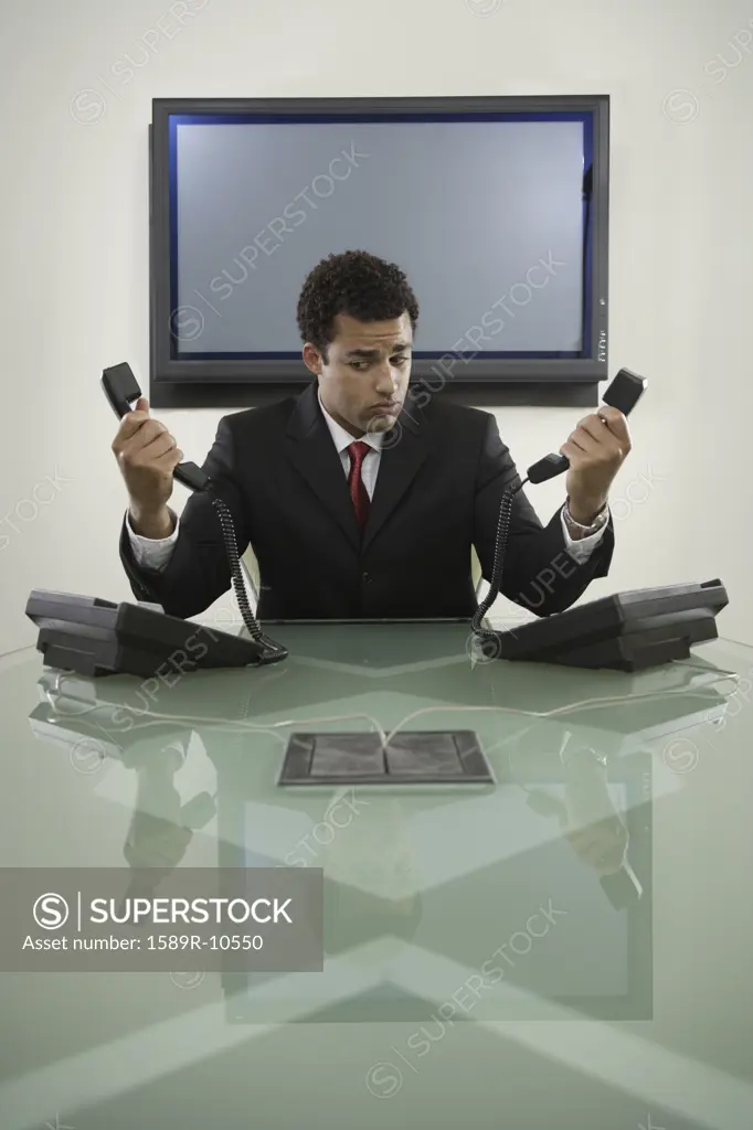 Businessman holding two telephones