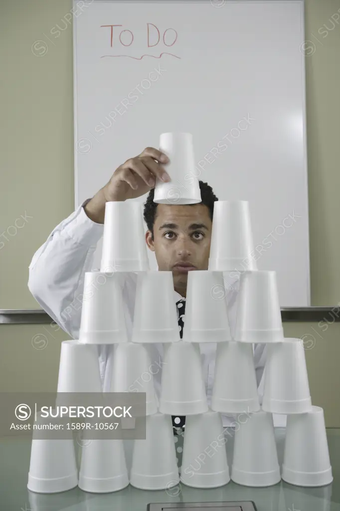 Businessman building pyramid of styrofoam cups