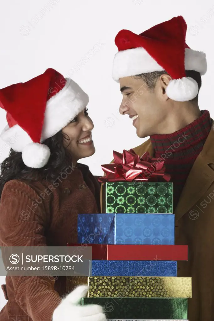 Young couple wearing Santa hats with gifts