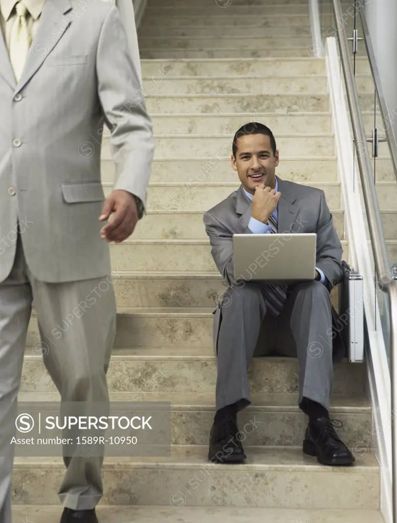 Businessman sitting on steps with laptop