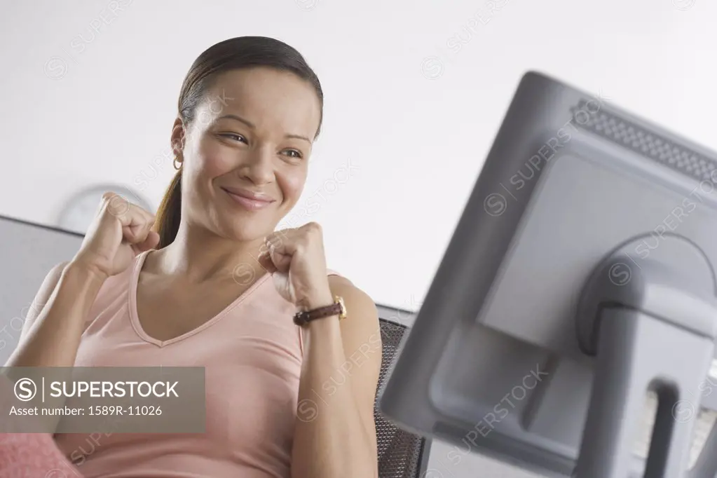 Woman cheering while looking at computer