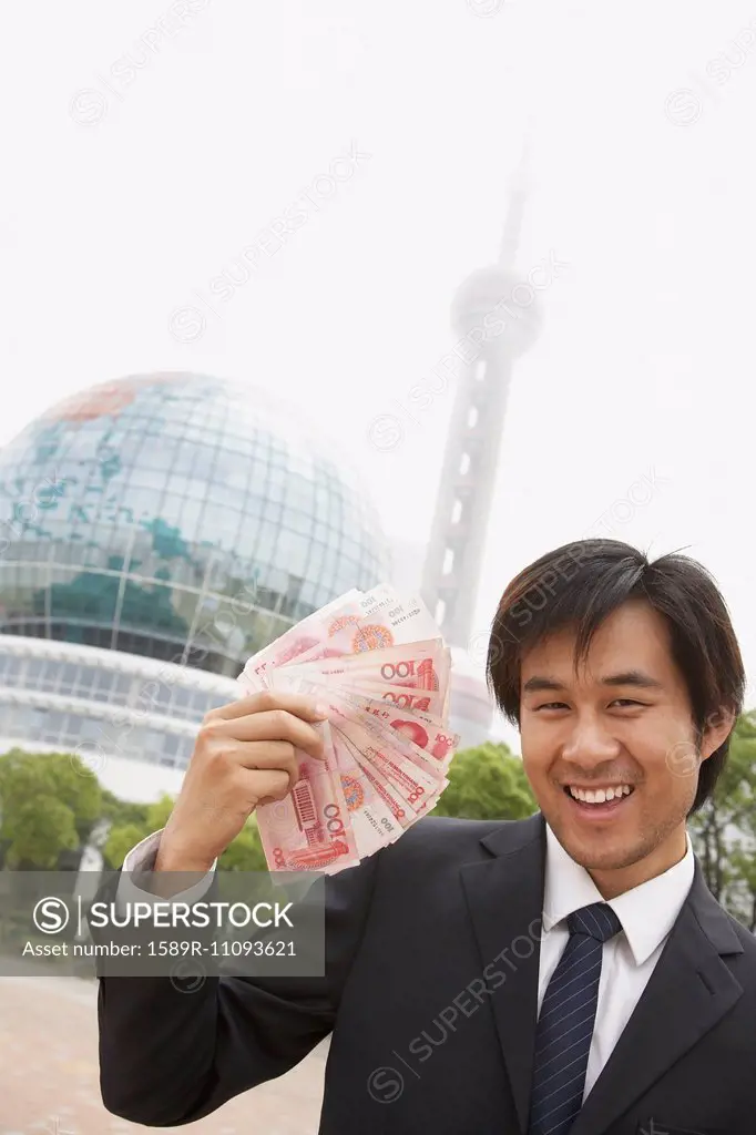 Chinese businessman holding wad of money, Shanghai, China
