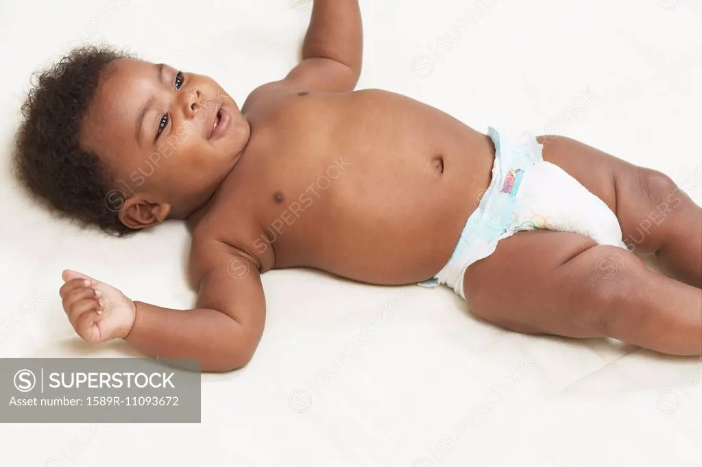 Black baby laying on bed