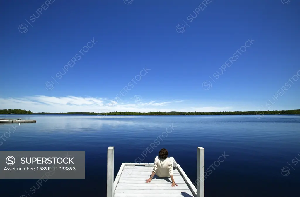 Woman overlooking lake on wooden dock