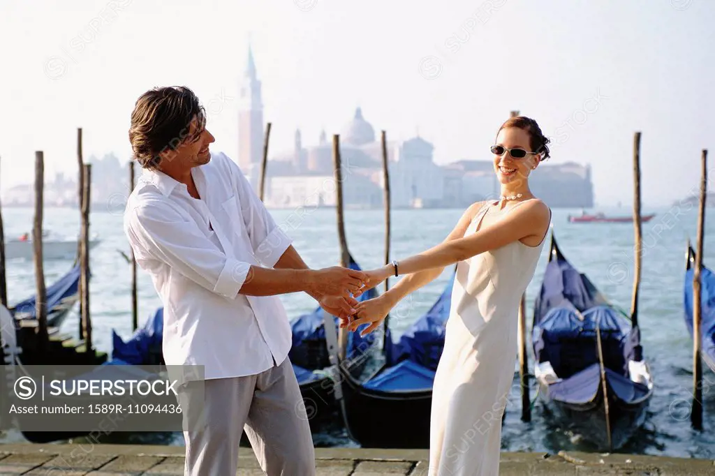 Couple holding hands on urban canal front, Venice, Veneto, Italy