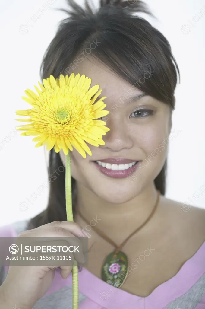Portrait of a young woman holding a flower smiling
